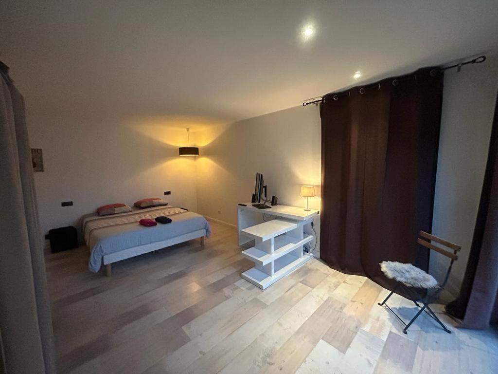 a bedroom with a bed and a table and a chair at Intime et tranquille in Vernouillet