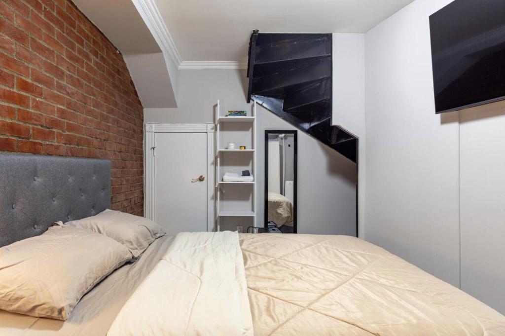 een slaapkamer met een bed en een bakstenen muur bij Room at the heart of East Village 1 in New York