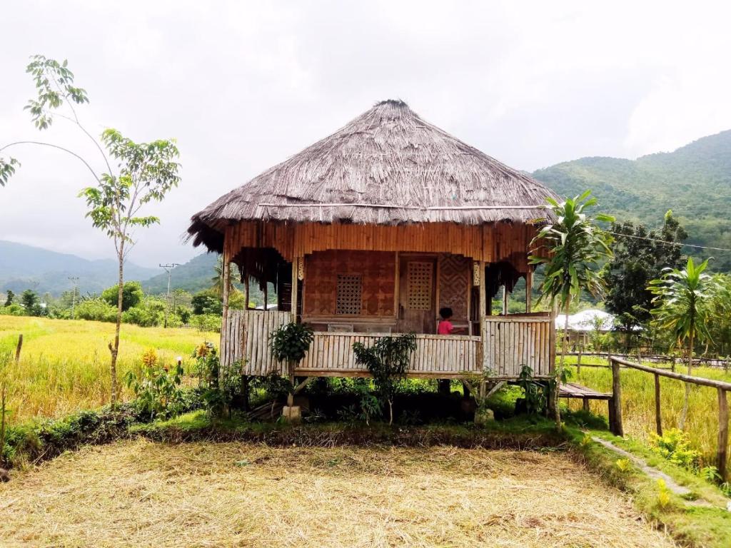 a hut in a field with a person sitting in it at Tado Homestay in Limbung