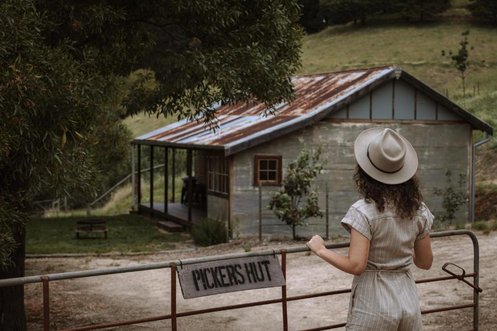 a woman in a hat looking at a small shack at Pickers Hut in Basket Range