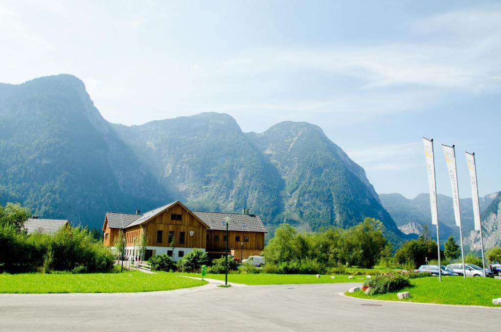 un edificio con montañas al fondo con aparcamiento en Dormio Hotel Obertraun, en Obertraun