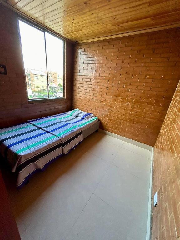 Habitación pequeña con cama en una pared de ladrillo en El pinar, Dindalito, en Bogotá
