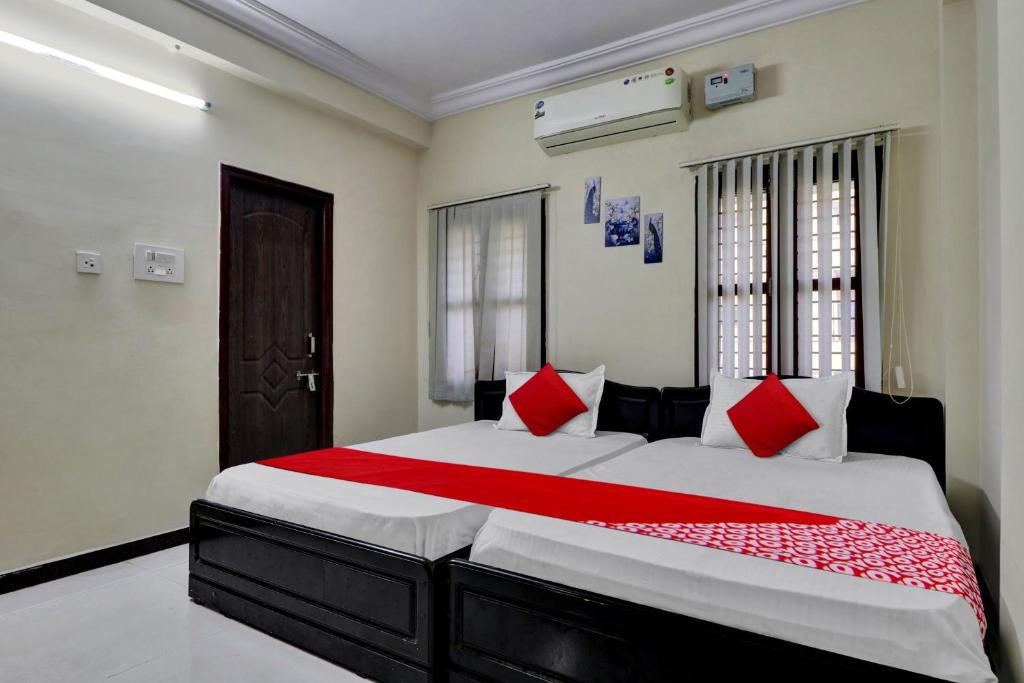 - une chambre dotée d'un grand lit avec des oreillers rouges et blancs dans l'établissement OYO Shri Inn, à Vijayawada