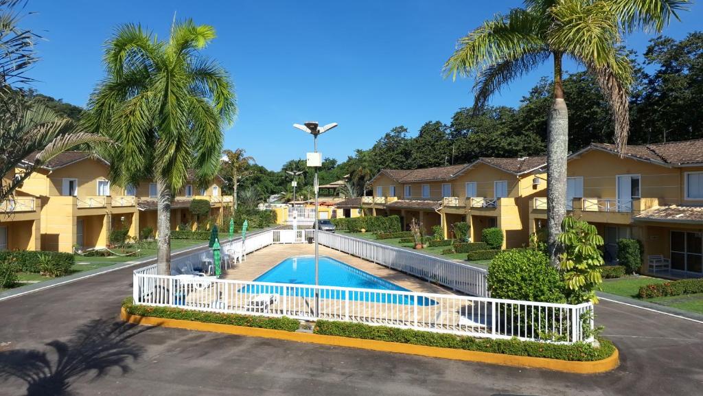 une villa avec une piscine et des palmiers dans l'établissement VILLAGIO CHARMOSO NA PRAIA DA MOCOCA, à Caraguatatuba