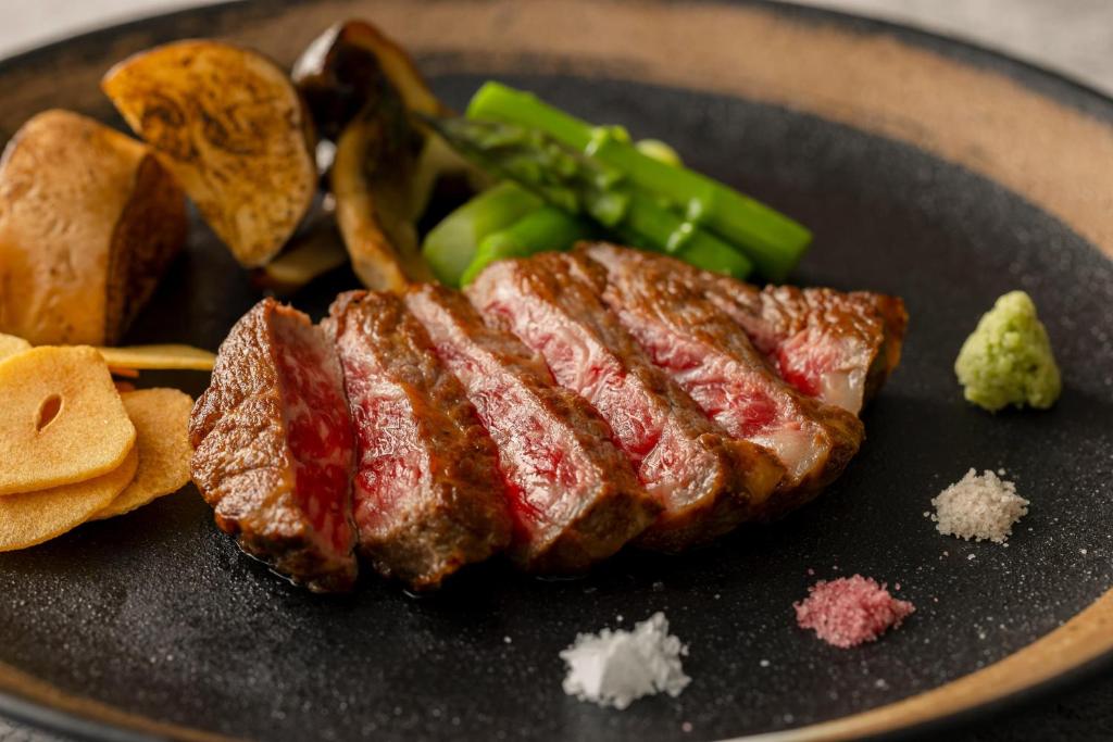 a steak and vegetables on a black plate at Rihga Royal Hotel Hiroshima in Hiroshima