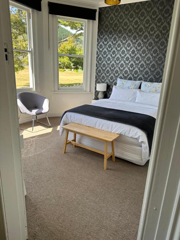 a bedroom with a bed and a chair and a window at SHORT WALK TO NELSON CITY CENTRE - Quiet location, comfy beds, pet friendly, full kitchen, claw-foot bath tub, outdoor areas in Nelson