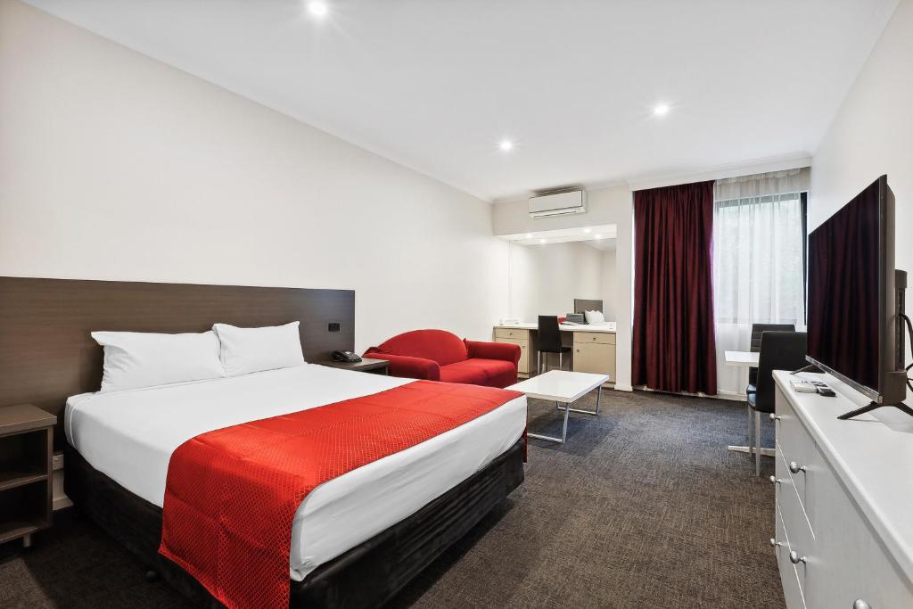 Habitación de hotel con cama y silla roja en Quality Hotel Manor en Mitcham