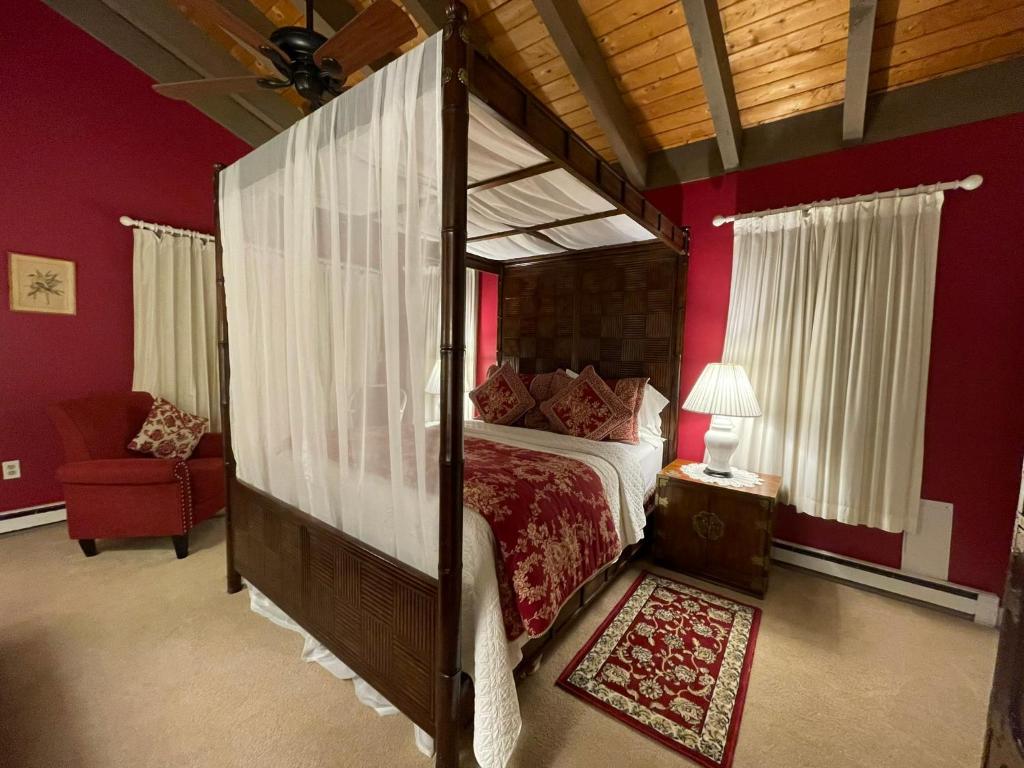 1 dormitorio con cama con dosel y pared roja en Deerhill Inn, en West Dover