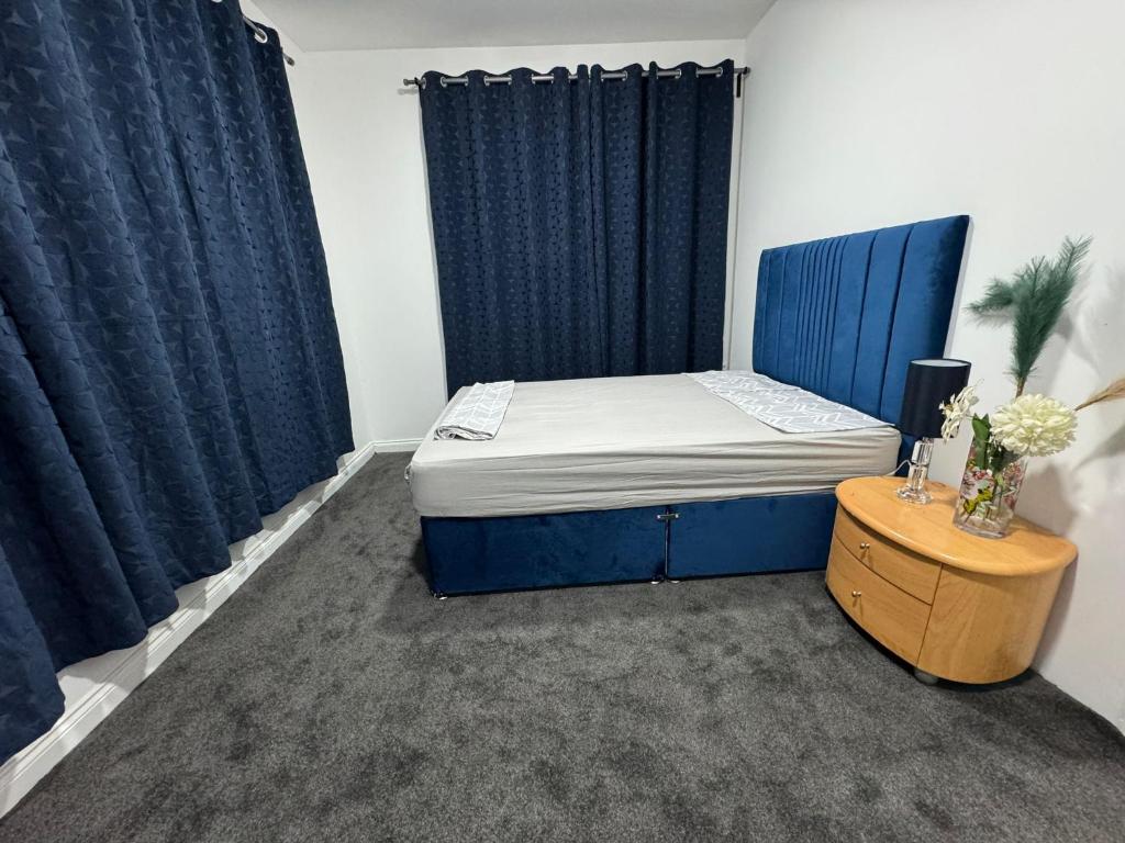 a bedroom with a blue bed and blue curtains at Flat in Cheam in Sutton