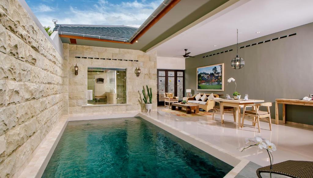 a pool in the middle of a living room with a dining room at Alindra Villas & Spa in Nusa Dua