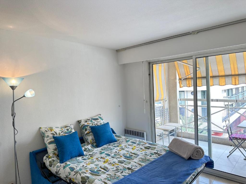 une chambre avec un lit avec des oreillers bleus et une fenêtre dans l'établissement Charming Apartment in Cannes 10-min to beach, à Cannes