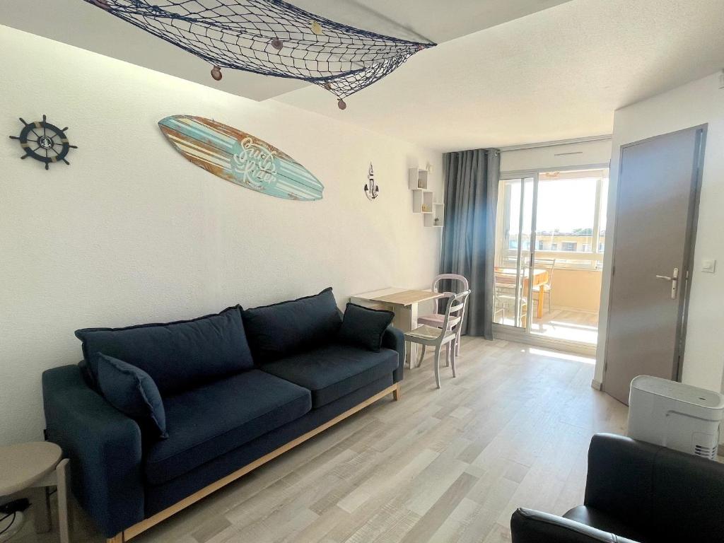 - un salon avec un canapé et une planche de surf sur le mur dans l'établissement Charmant T2 rénové à 50m de la plage, terrasse OUEST, près des commerces - FR-1-748-24, à Canet