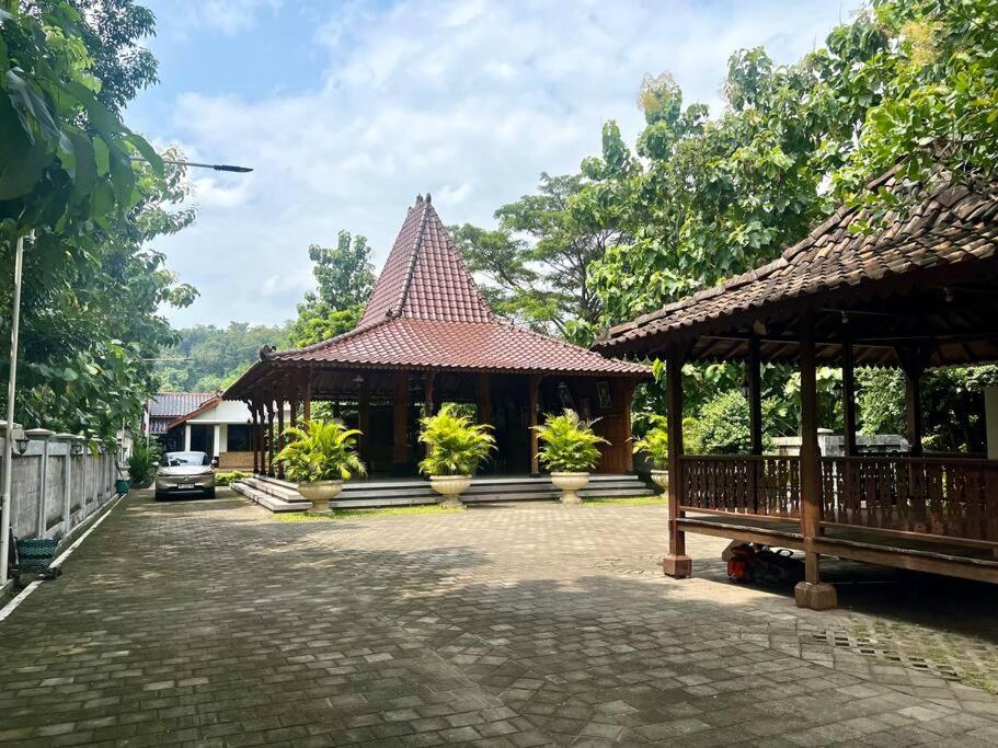 Joglo Satrio Pinayungan Villa في Piyungan: جناح بجناح مع مقعد ومبنى