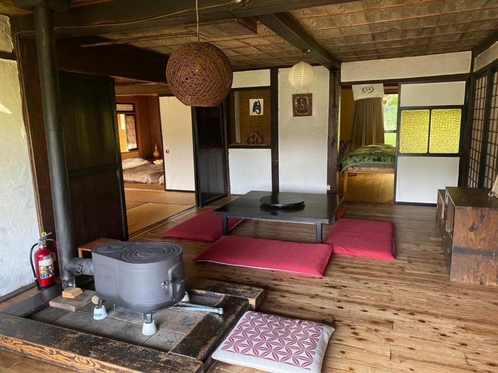 a room with a stove and red mats on the floor at KOMINKA guest house in Omachi
