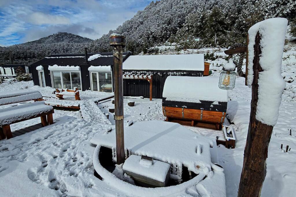 un patio cubierto de nieve con un edificio en Confortable refugio de monataña con vista al Volcan, en Malalcahuello