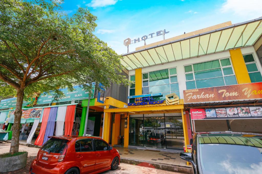 ein rotes Auto, das vor einem Gebäude parkt in der Unterkunft Golden Roof Hotel, Seri Iskandar in Seri Iskandar