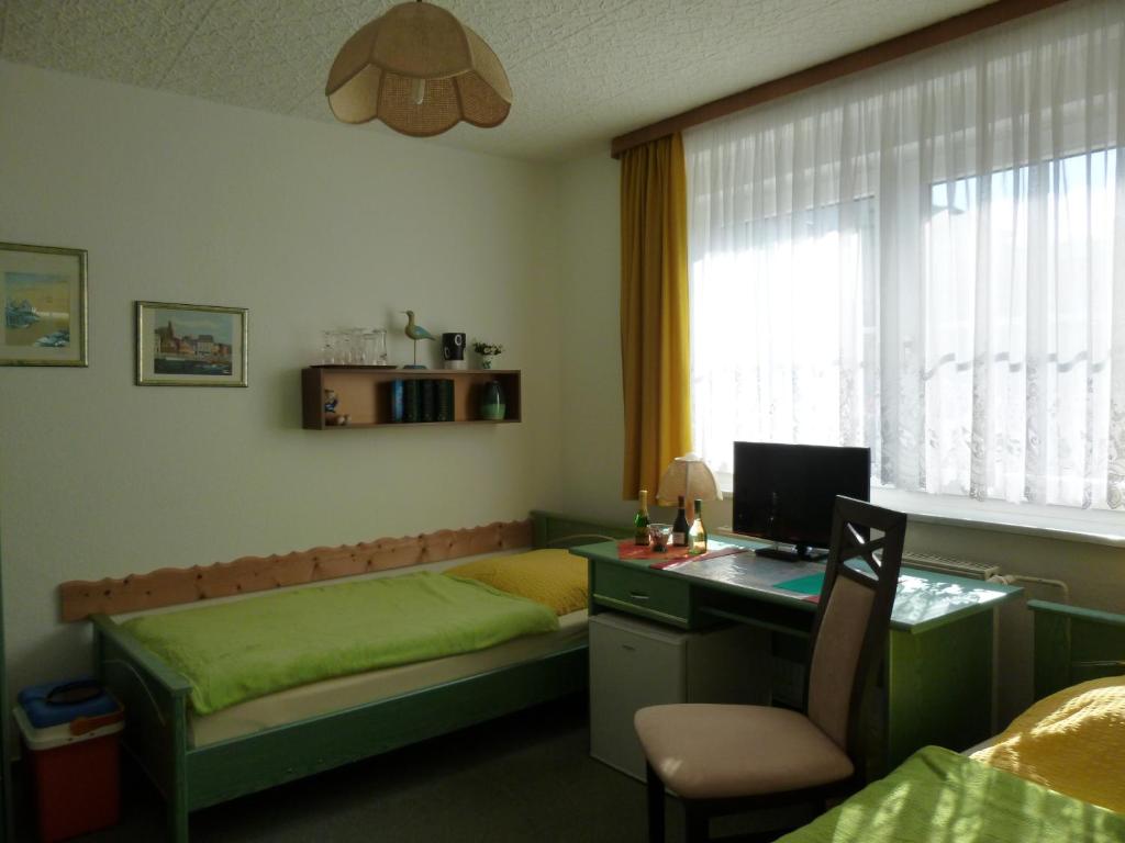 a bedroom with a bed and a desk with a computer at Pension am Peeneufer UG in Wolgast