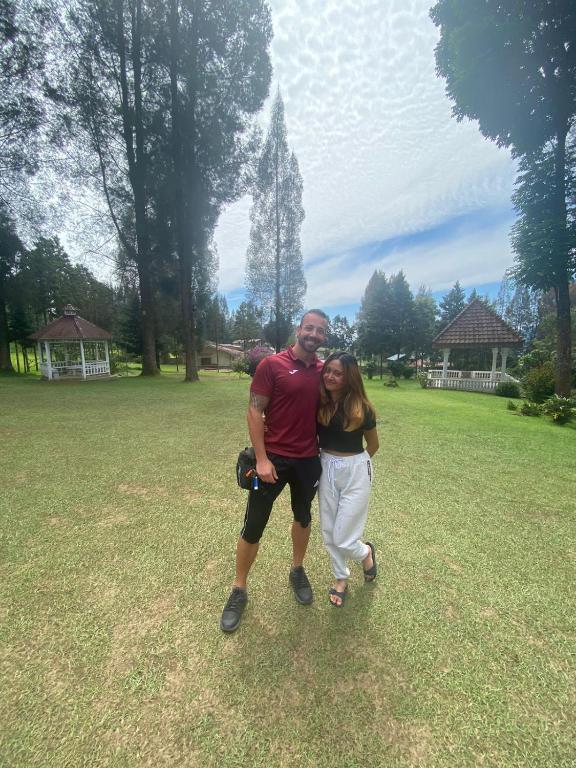 a man and woman posing for a picture in a field at Sibayak Multinational Rest House in Berastagi