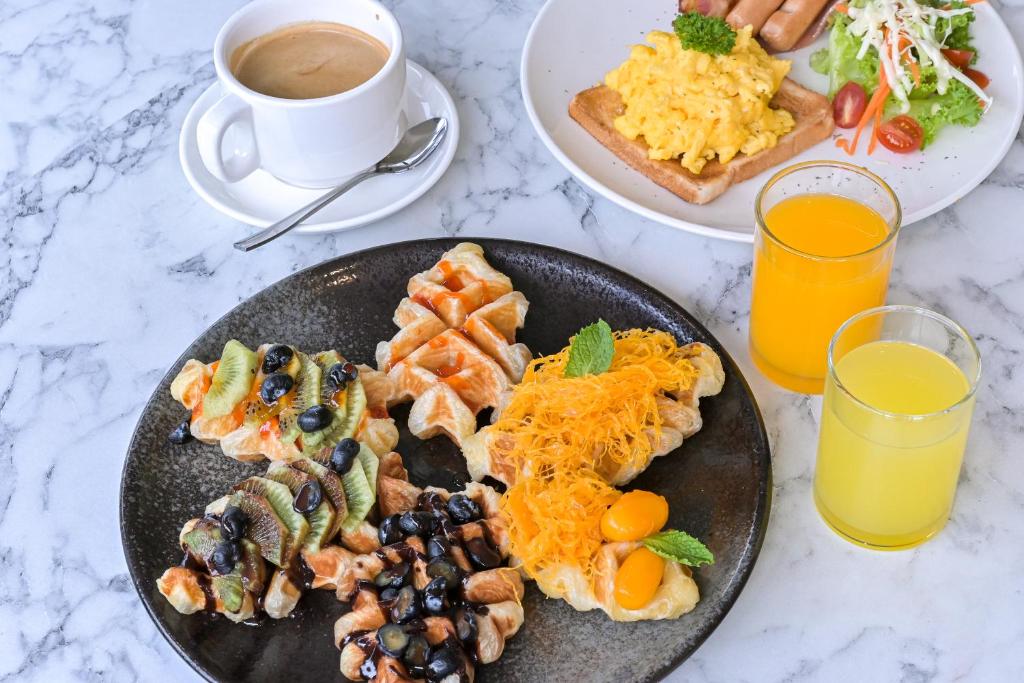 A breakfast table pairs coffee and juices with eggs, sausages, toast and fruit pastries.