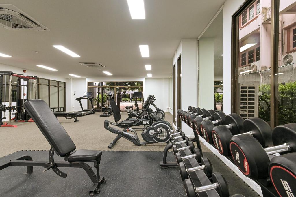 A bright fitness room with free weights, benches and cardio equipment.