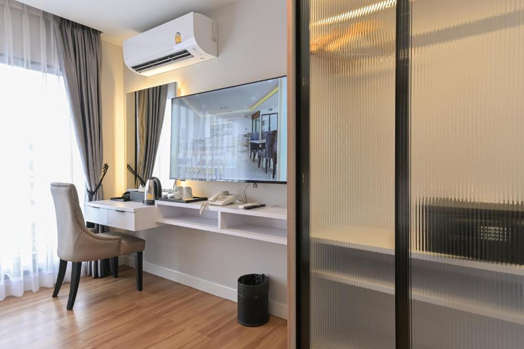 A compact in-room work area beside a curtained window and screened sleeping zone.