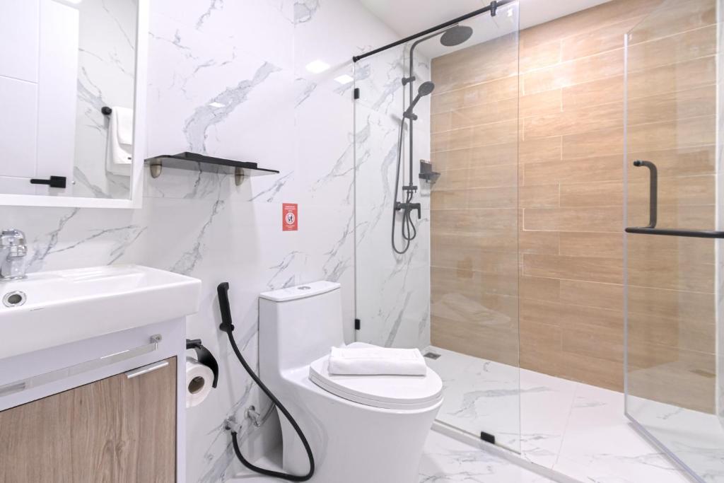 A bright bathroom with a glass-enclosed rainfall shower, toilet and vanity.