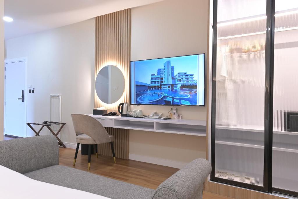 A bedroom sitting area with a wall-mounted television, desk, and tea station.