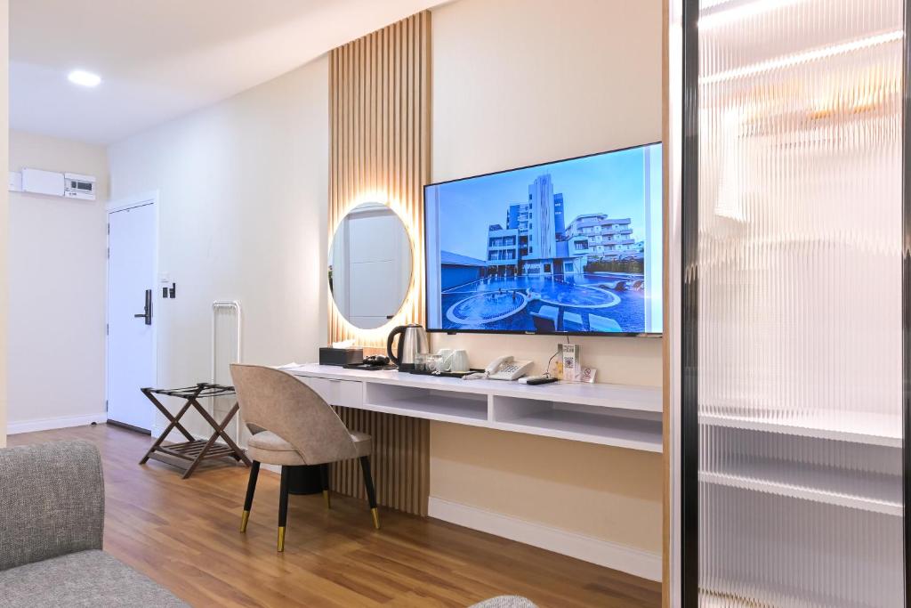 A compact in-room work area with a desk, chair, television and refreshment setup.