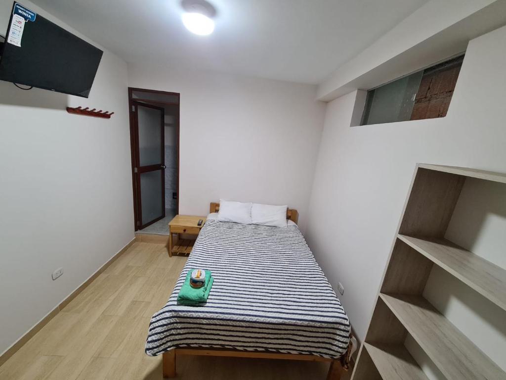 Zimmer mit einem Bett in einem Zimmer mit einem TV in der Unterkunft LIRI House in Oxapampa