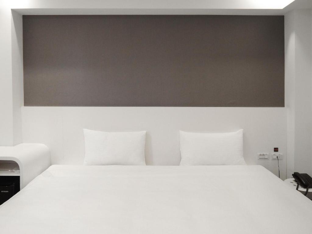 Un dormitorio con una cama blanca con una gran colcha blanca en CHECK inn Express Taipei Yongkang en Taipéi
