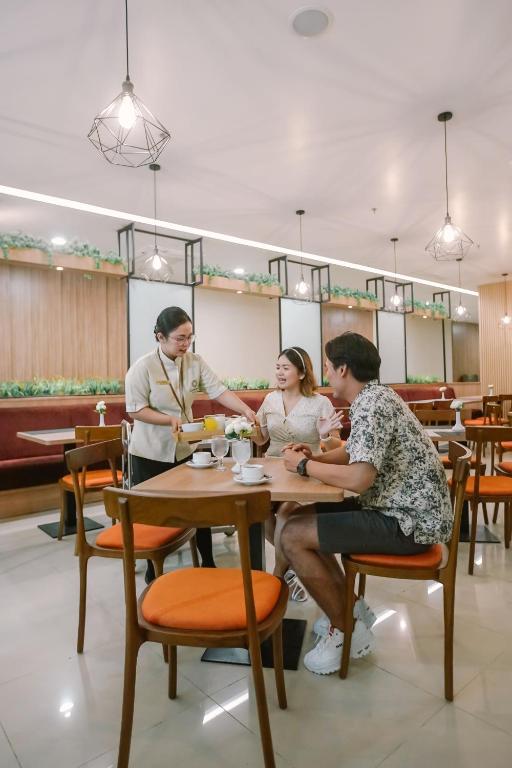 a group of people sitting at a table in a restaurant at Cordia Hotel Yogyakarta - Hotel Dalam Bandara in Glagah