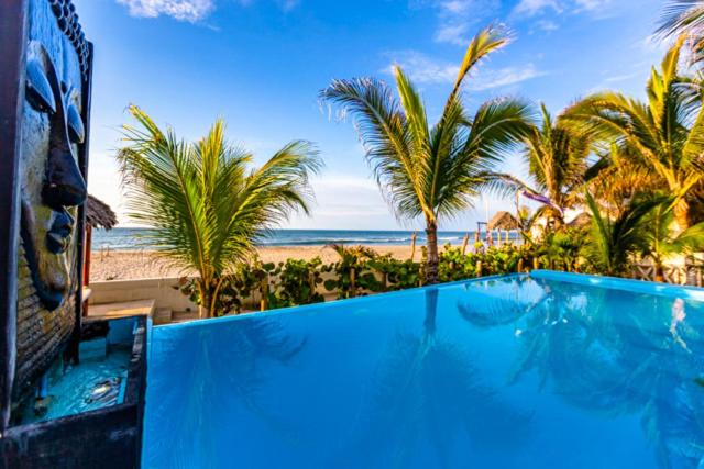una piscina azul junto a una playa con palmeras en Casa Estrella de Mar, en Zorritos