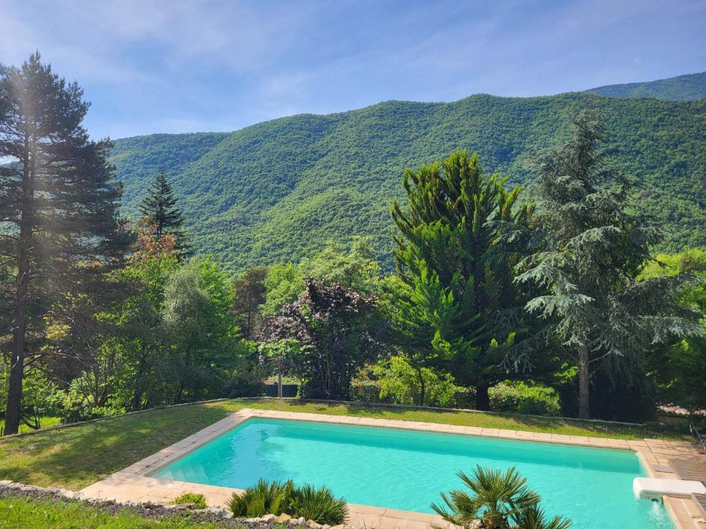 una piscina con una montaña en el fondo en Lou mas del ranc, en Roquestéron