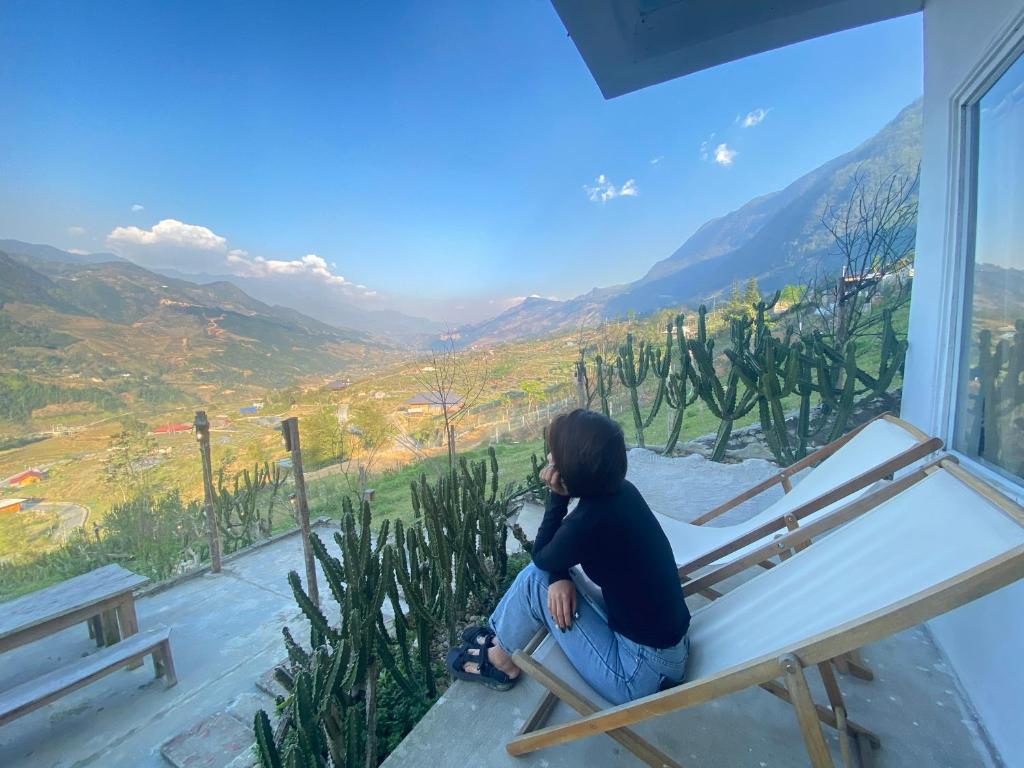 a woman sitting on a bed in a room with a view at Pavi home in Sa Pa