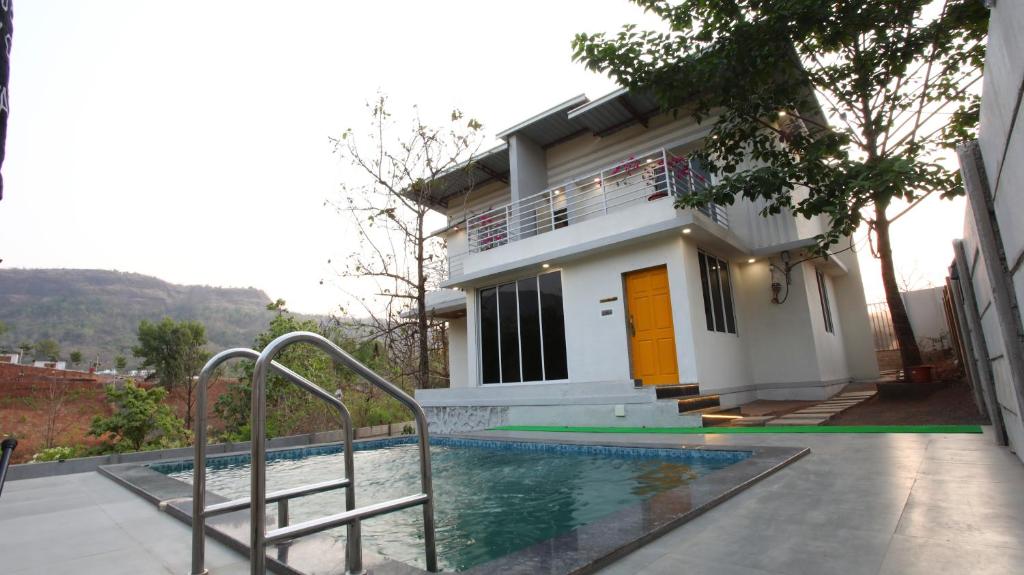 dom z basenem przed nim w obiekcie Aum Villa Pet Friendly w mieście Karjat