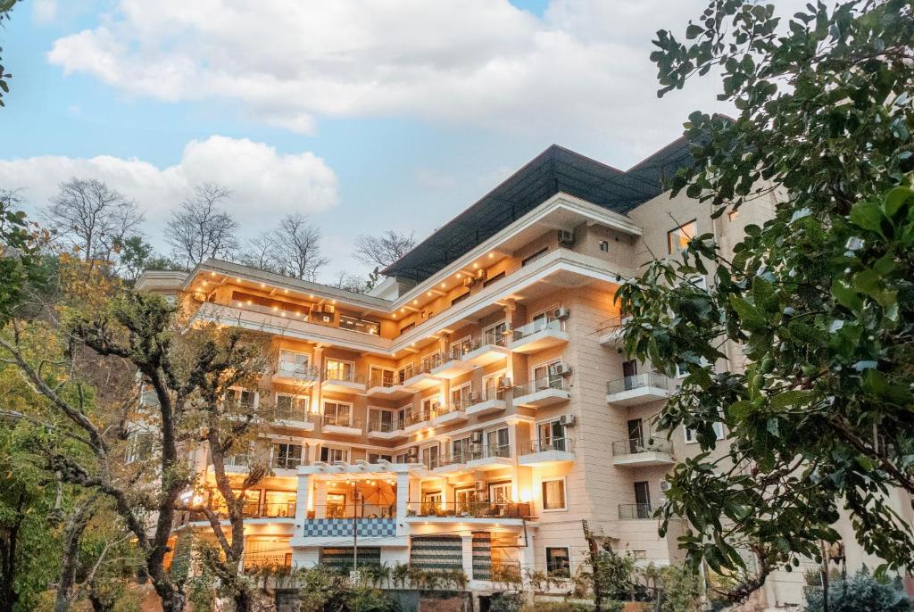 un gran edificio blanco con árboles en el primer plano en Stone Wood Hotel, Rishikesh, en Rishīkesh