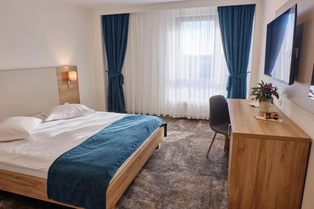 a hotel room with a bed and a desk and a bed sidx sidx sidx at Hotel Regal in Braşov