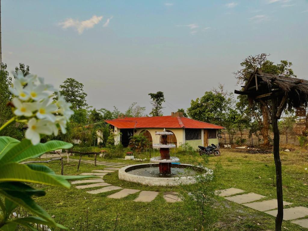 una fontana in un cortile con una casa sullo sfondo di Grand Narmada Homestay Resort-Bandhavgarh a Tāla