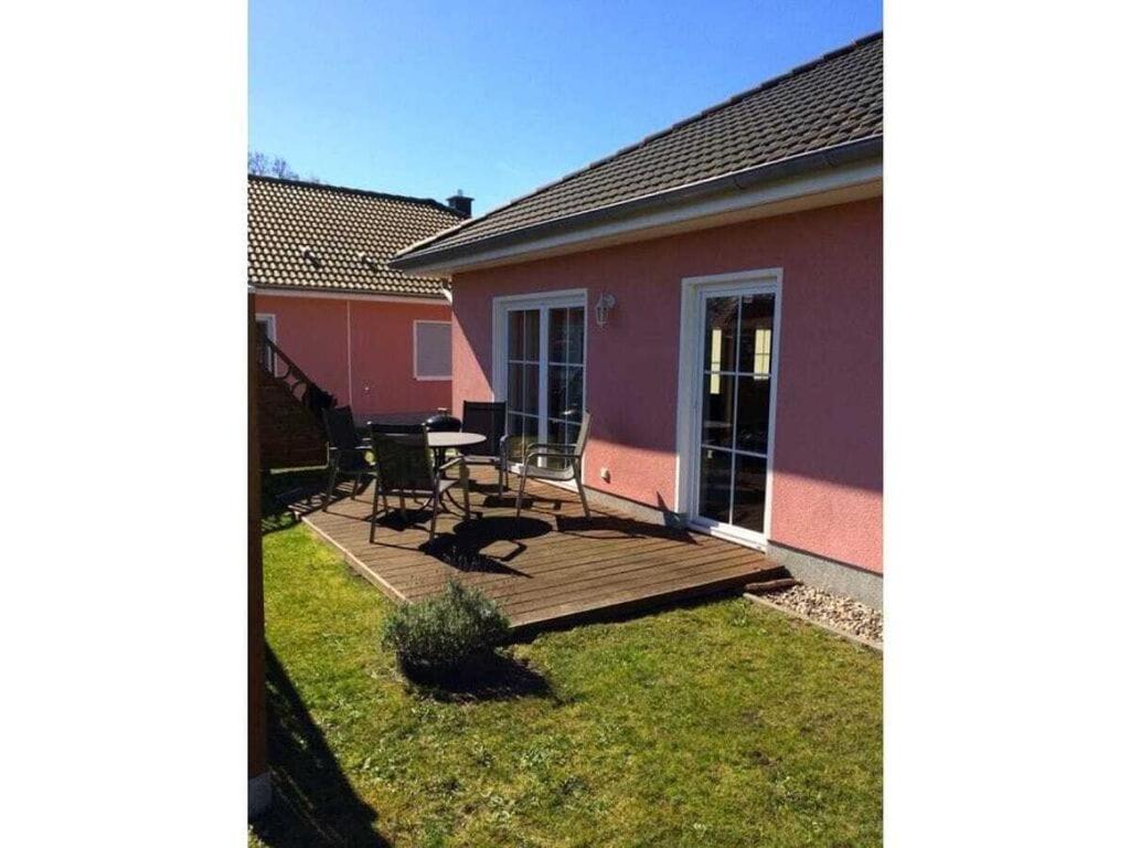Casa con terraza de madera con mesa y sillas en Boddensurfer 3a, en Pruchten