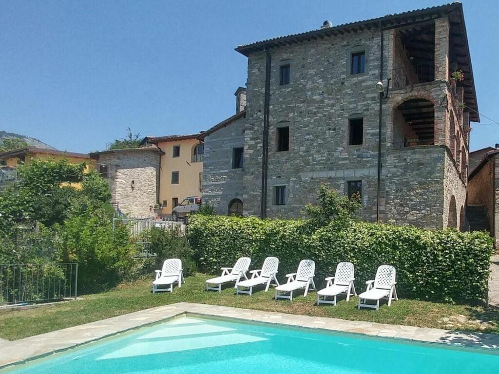 - un groupe de chaises et une piscine en face d'un bâtiment dans l'établissement Holiday house with pool exclusive use, à Magnano