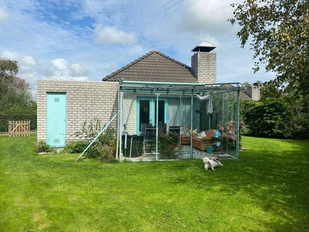 a small house with a dog in the yard at Noordzee omheind met hond in Dirkshorn