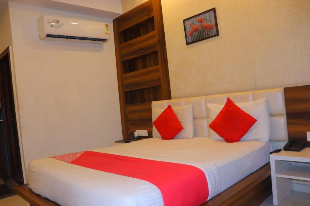 Cette chambre comprend un lit avec des oreillers rouges. dans l'établissement HOTEL LORDS IN, à Ahmedabad