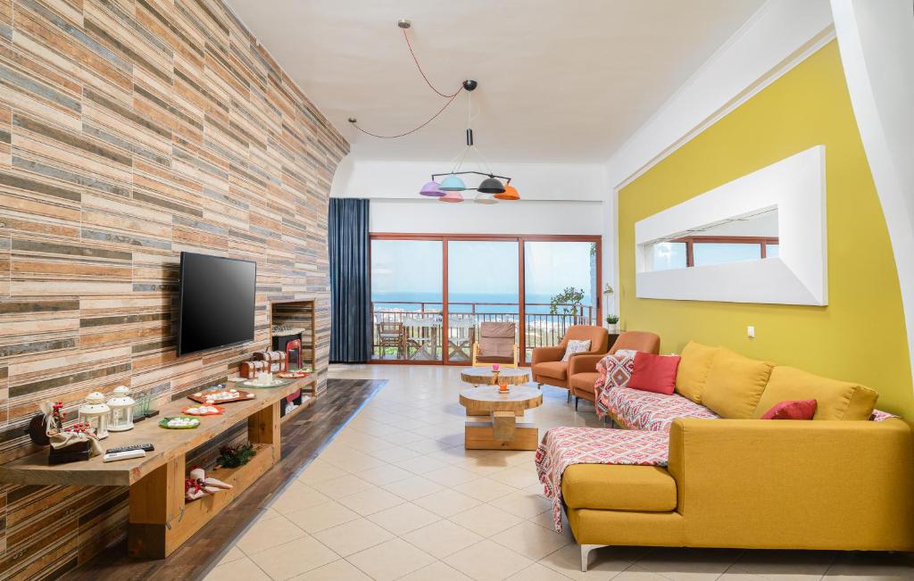 a living room with a yellow couch and a tv at More Crete Village House Koutouloufari in Hersonissos