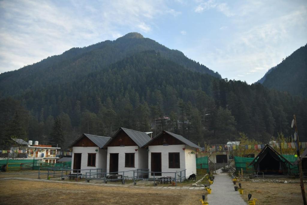 a small building with a mountain in the background at Himtrek Stays, Kasol in Kasol