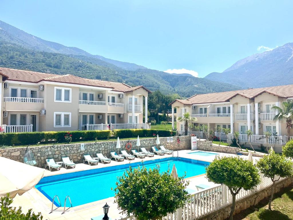 un complejo con piscina y montañas de fondo en Larimar Suite Hotel, en Ölüdeniz