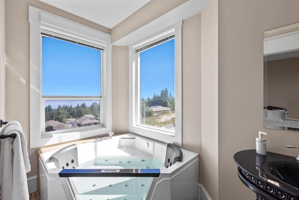 a bathroom with a tub and two windows at Seaview Executive Home in Ladysmith