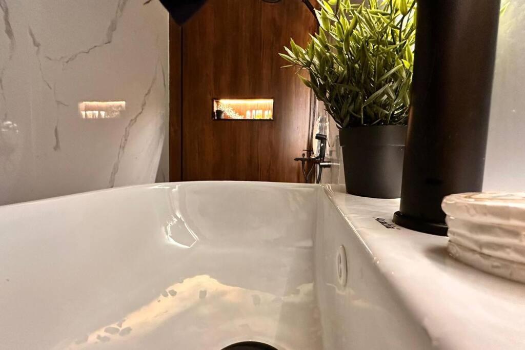 a white bath tub with a potted plant in a bathroom at شقة فاخرة بغرفة سينما وحديقة in Qabāʼ