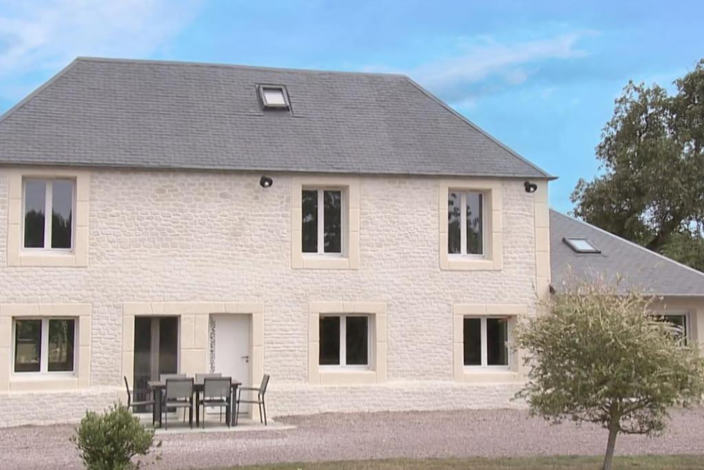 une grande maison blanche avec une table et des chaises dans l'établissement Maison de Campagne, à Saint-Cyr-du-Ronceray