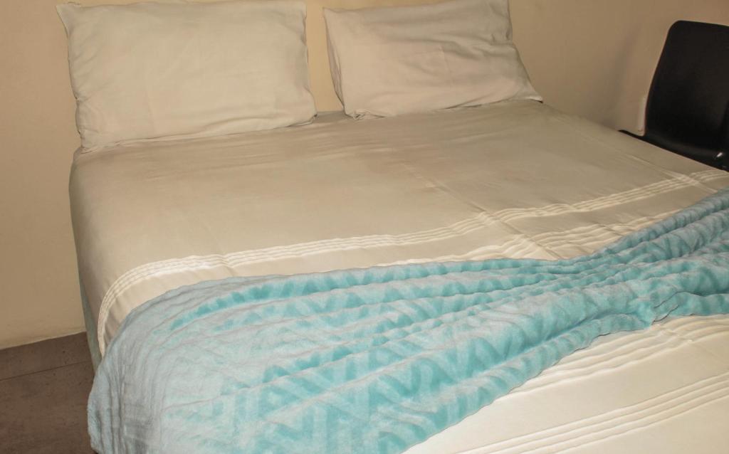 a bed with a blue and white blanket on it at Ingwenya Guesthouse in Ermelo