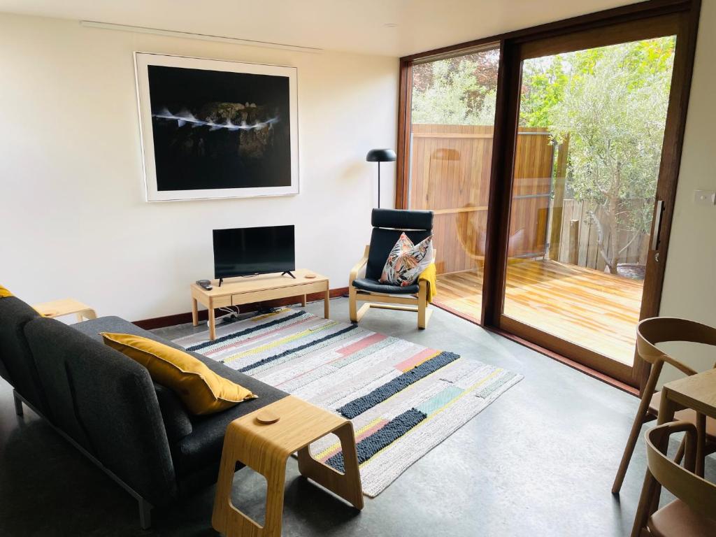 uma sala de estar com um sofá e uma cadeira e uma televisão em Cascade Pad in South Hobart em Hobart